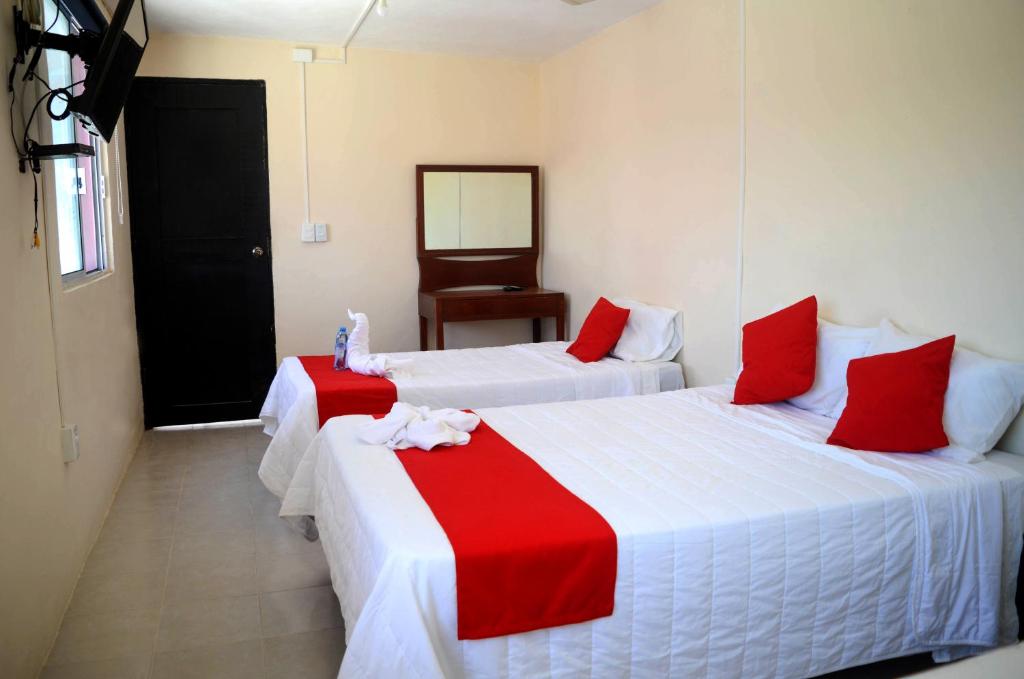 two beds with red and white sheets in a room at Hotel Rosa del Alba in Chetumal