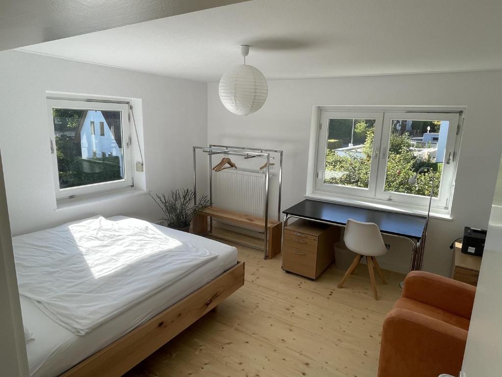 a bedroom with a bed and a desk and two windows at Hofberg Villa in Landshut