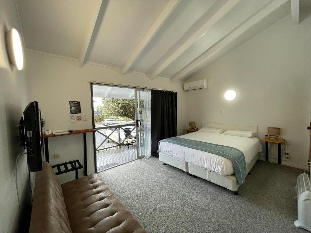 a bedroom with a bed and a couch and a window at Siesta Motel in Auckland