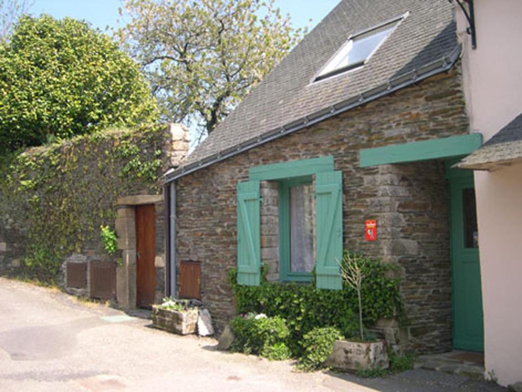 ein Backsteinhaus mit grünen Rollläden und einem Fenster in der Unterkunft Les Locations du Puits in Rochefort-en-Terre