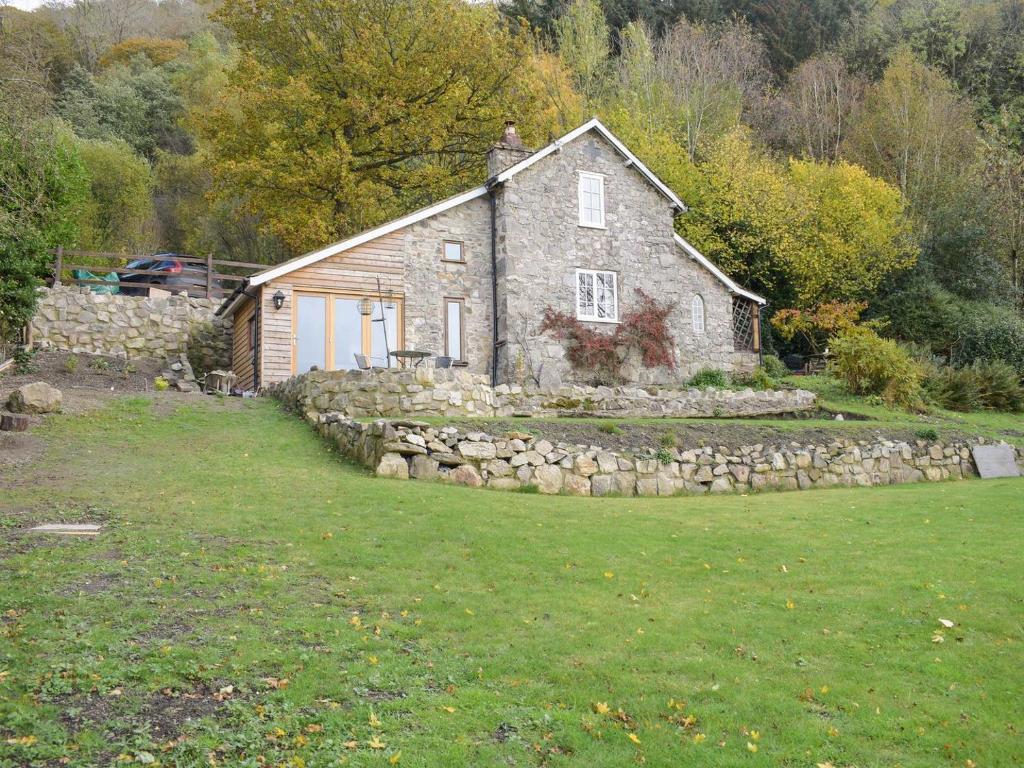 an old stone house with a stone wall at Pentre Cwm Bach in Llansilin