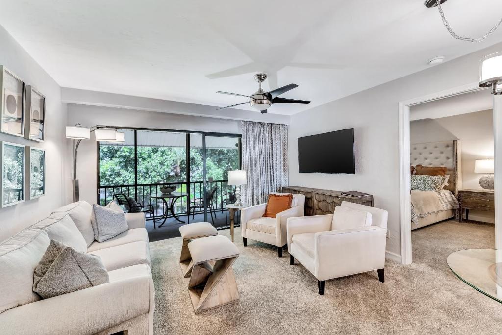 a living room with white furniture and a tv at A Foot in the Shore in Naples