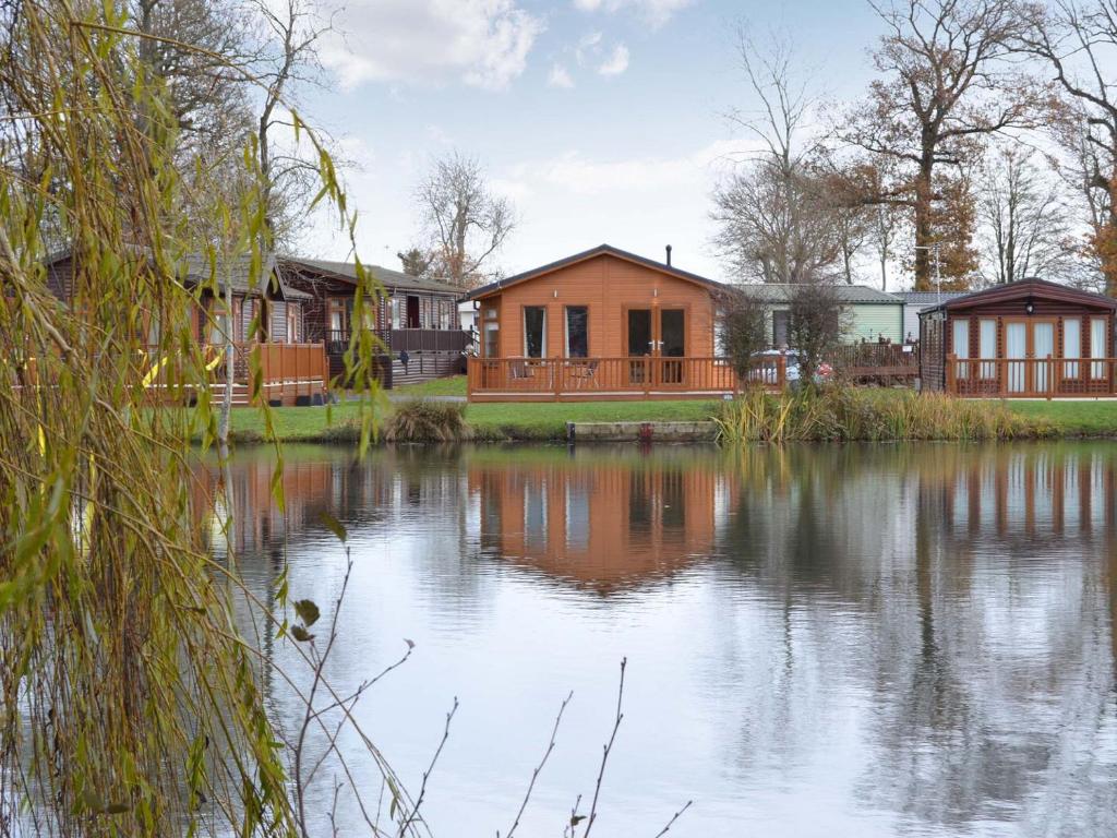 a house next to a lake with buildings at Lakeside in Kelsale