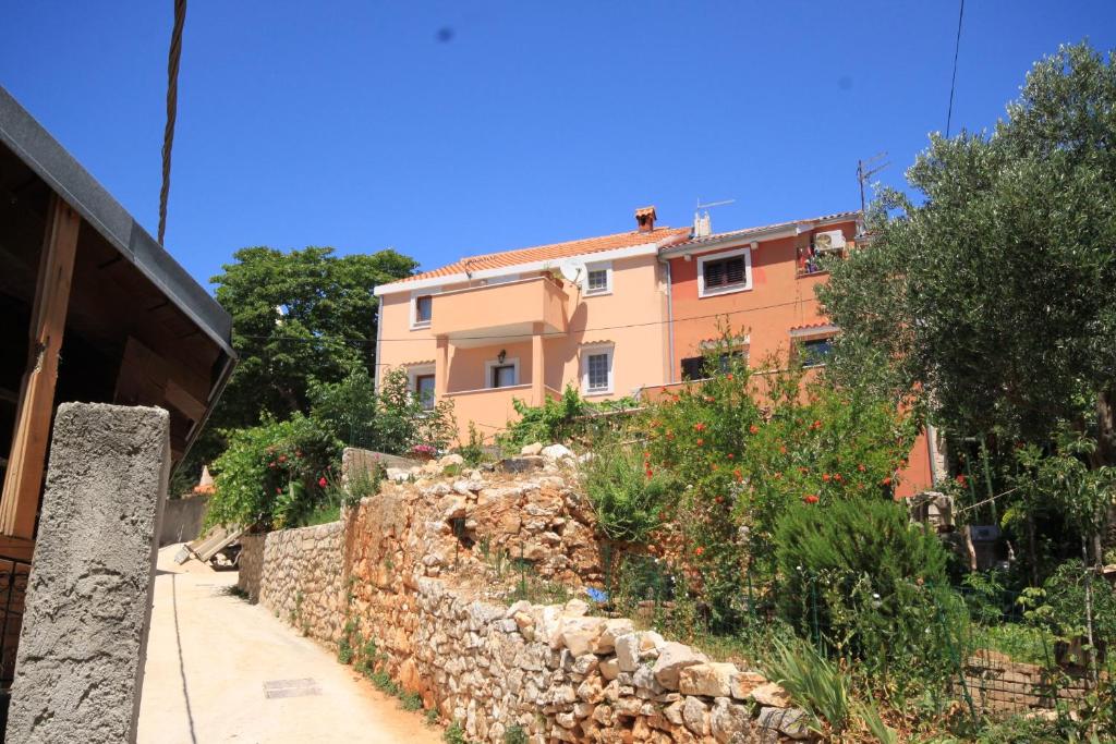a building in front of a stone wall at Apartments with a parking space Cunski, Losinj - 8010 in Cunski