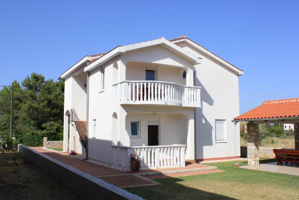 Biały dom z balkonem i dziedzińcem w obiekcie Apartments by the sea Pasman - 8215 w mieście Pašman