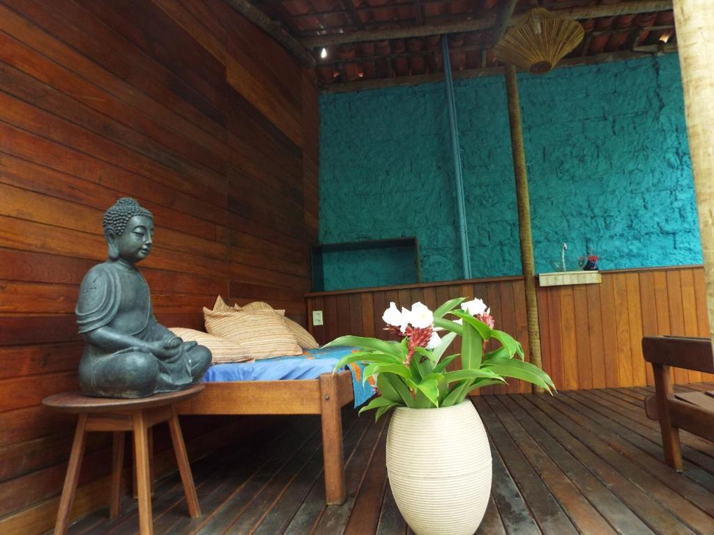 Pokój z posągiem Buddy siedzącym na łóżku w obiekcie JARDIM UXUA w mieście Ilha de Boipeba
