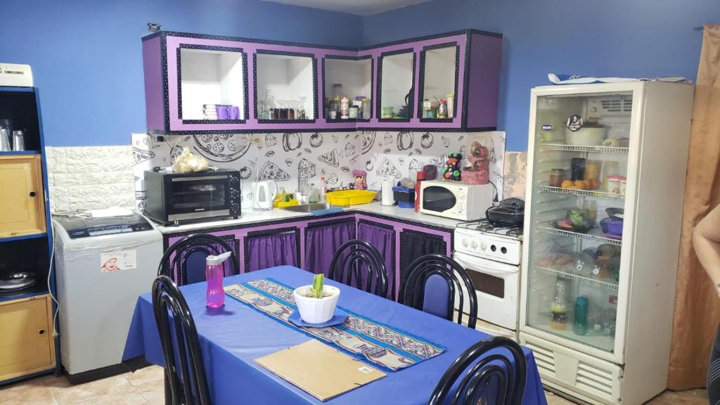 kuchnia z fioletowymi szafkami, stołem i lodówką w obiekcie La casa de valle w mieście Termas de Río Hondo