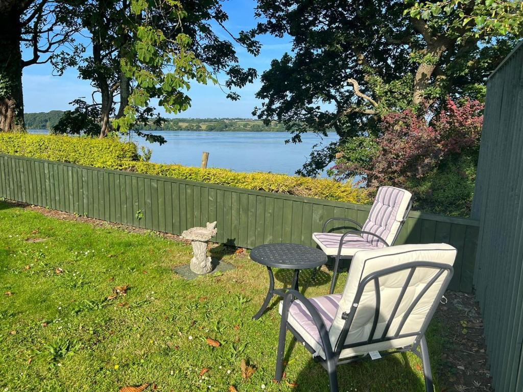 two chairs and a table with a view of a lake at Furzy Cottage in Haverfordwest