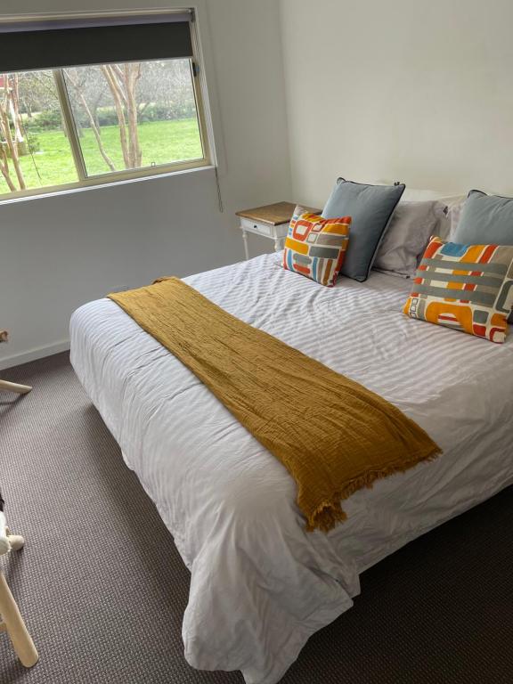 羅伯遜的住宿－Wallaby Cottage，卧室配有带枕头的大床和窗户。