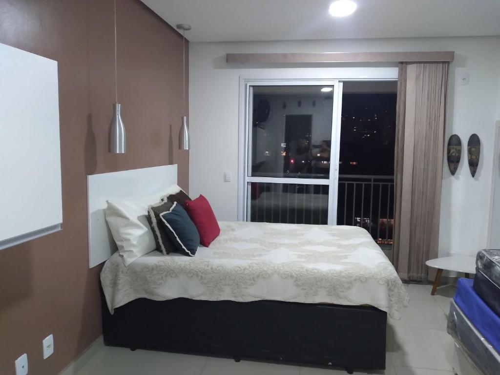 1 dormitorio con cama con almohadas y ventana en flat reg central sp varanda e Wi-Fi grátis 500 megas, en São Paulo