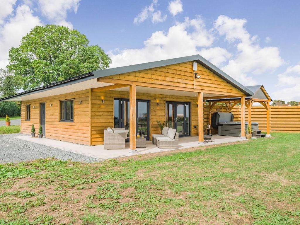a log cabin with a porch and chairs in a yard at Oak Tree Lodge - Uk38383 in Lyonshall