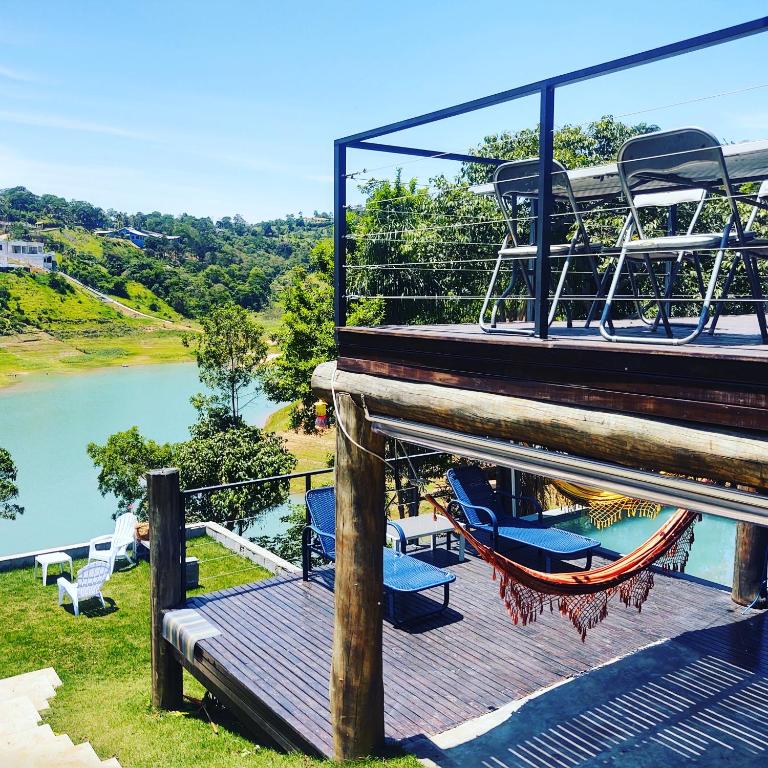 a deck with a hammock and a view of a river at Igarata Cabana da Sol in Igaratá