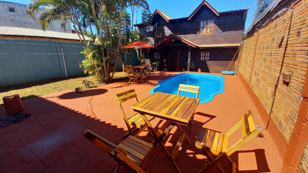 um pátio com uma mesa e cadeiras e uma piscina em Cabañas Marian 2 em Puerto Iguazú
