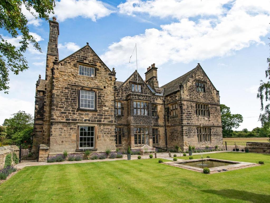 an old stone house with a large yard at Hodroyd Hall in Holmfirth