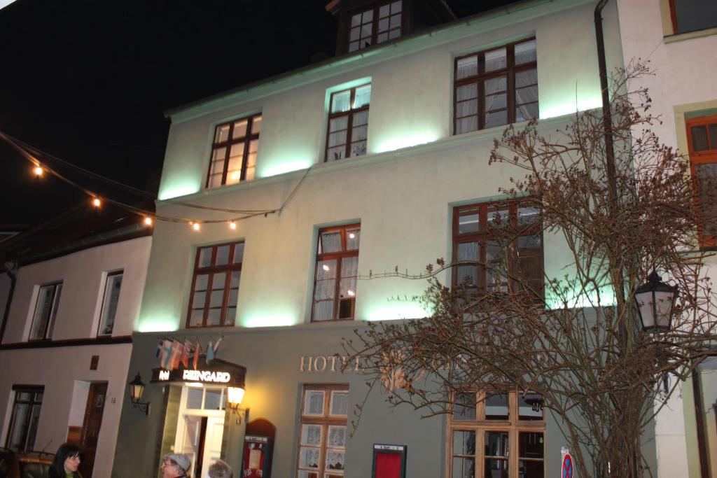 Un grand bâtiment blanc avec des lumières allumées la nuit dans l'établissement Hotel Reingard, à Wismar