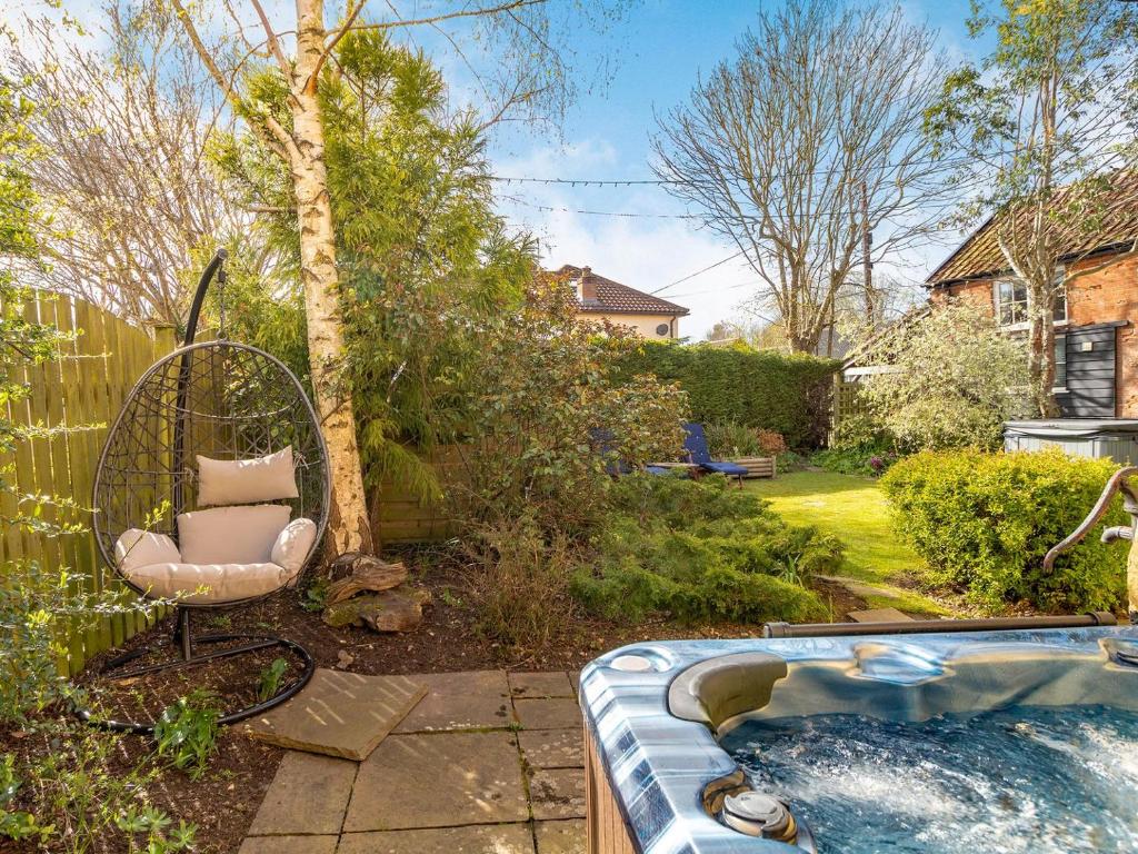 un patio trasero con un columpio y una piscina en Horseshoes House, en Watton