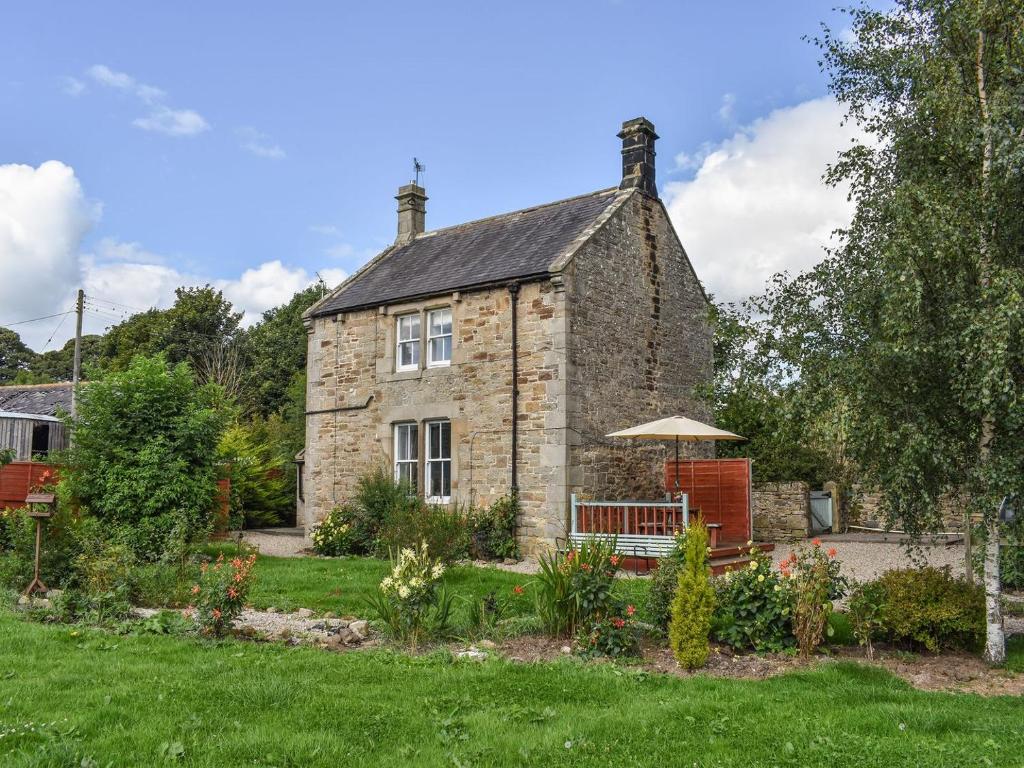 an old stone house with a garden in front of it at Keepershield Cottage in Gunnerton