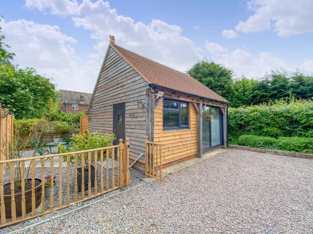 a small wooden cabin with a fence in a garden at The Potting Shed in Hinxhill