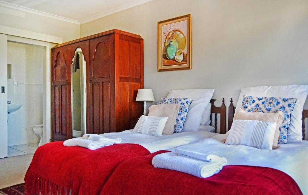a bedroom with two twin beds with red blanket at Chesham House in Hermanus