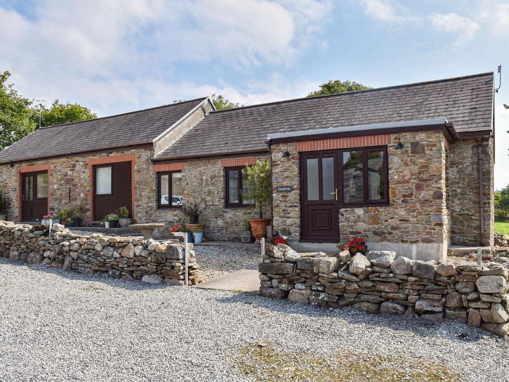 a stone house with a stone wall at Swallow Cottage in Gowerton