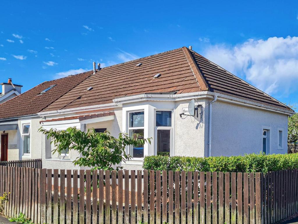 una casa blanca con techo marrón detrás de una valla en Kirklea, en Wishaw