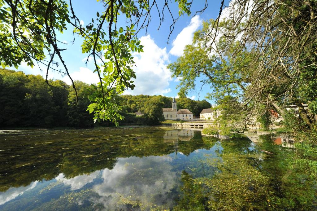 a view of a river with a house in the background at Gentilhommière Eaux Bleues in Écot-la Combe