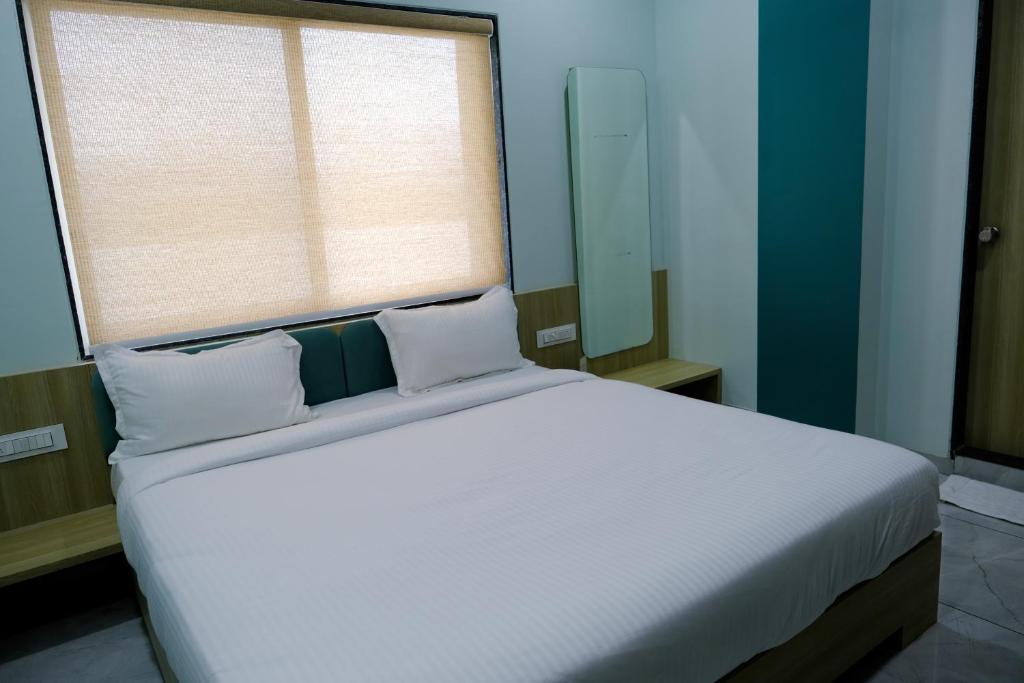 a bedroom with a large white bed with a window at Hotel Sai Unity Room in Garudeshwar