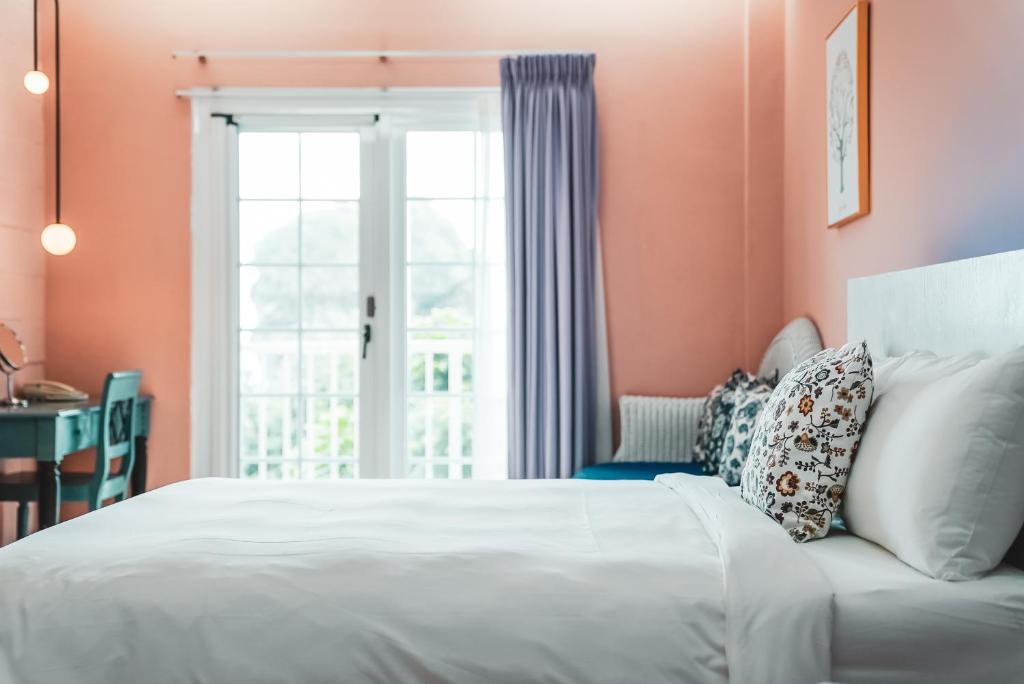 a bedroom with a white bed and a window at Canaan B&amp;B Kenting in Eluan