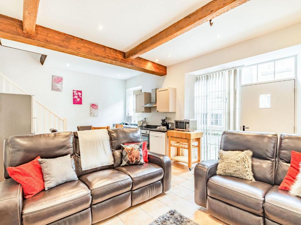 a living room with two leather couches and a kitchen at Shire Cottage - Uk37451 in Pateley Bridge