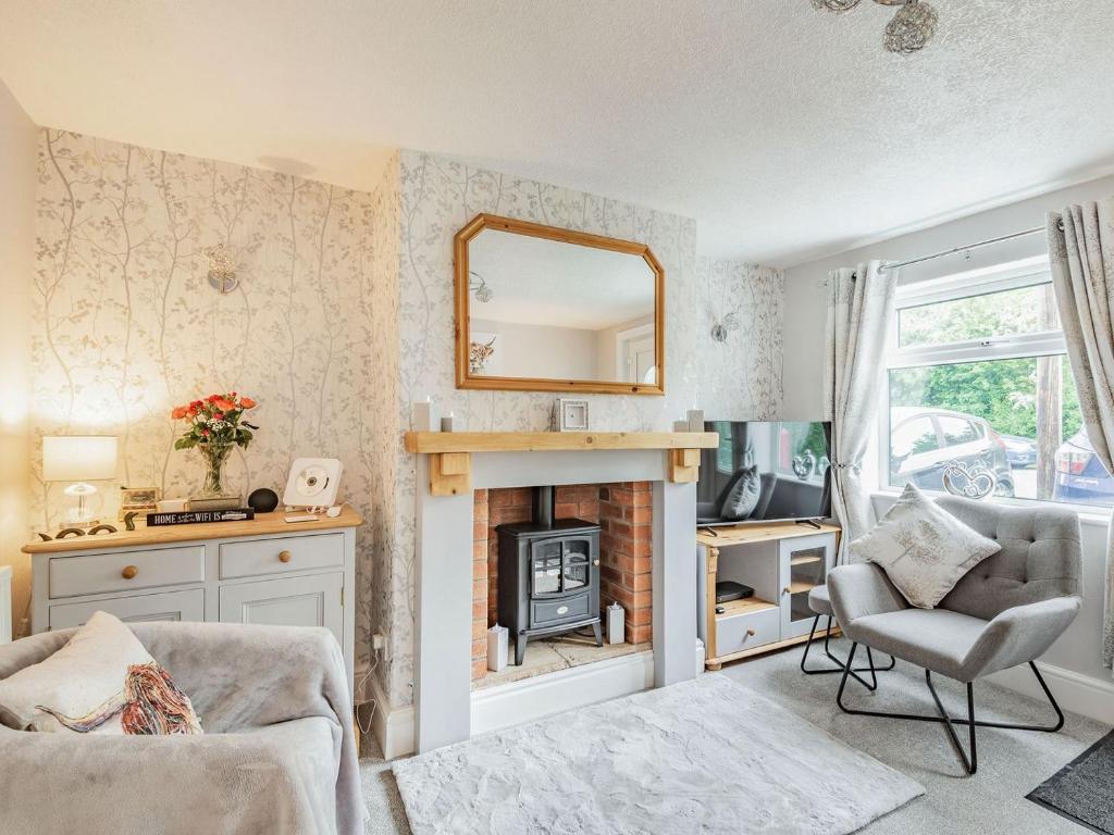 a living room with a fireplace and a mirror at Comfy Kozy Cottage in Louth