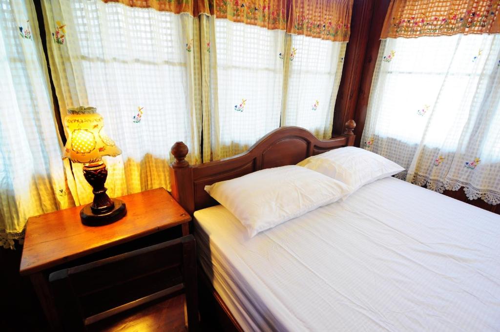 a bedroom with a bed and a lamp on a table at Kaloang home in Bangkok