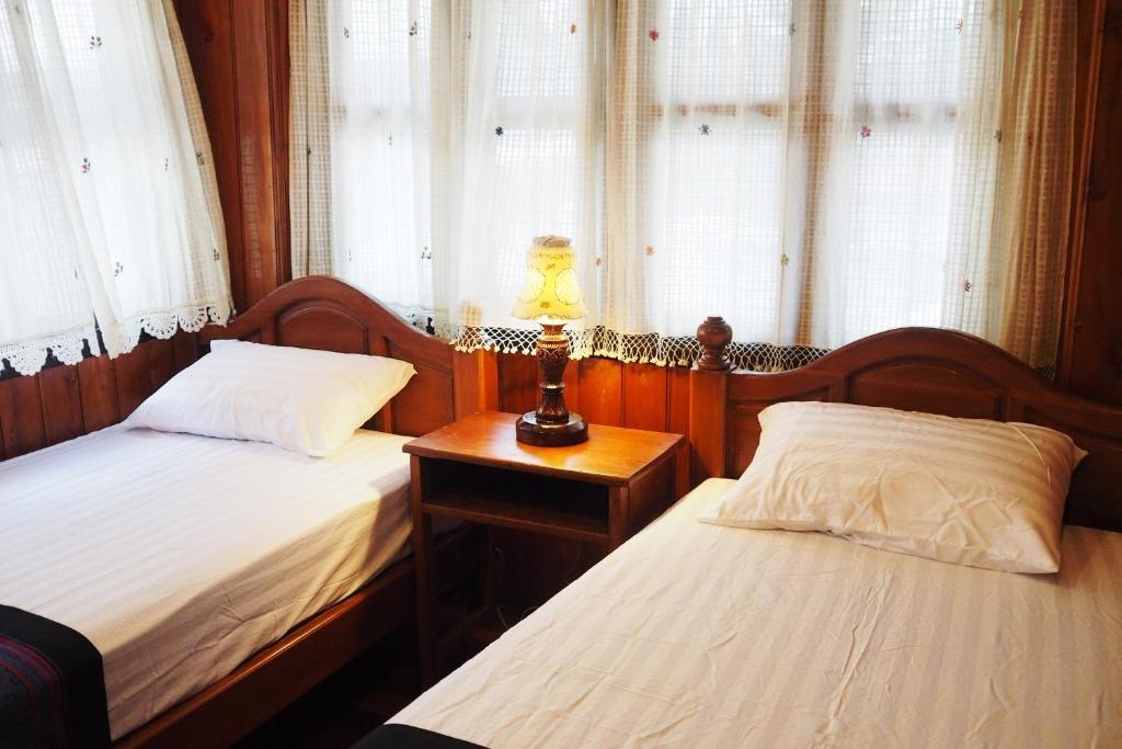 a bedroom with two beds and a lamp on a table at Kaloang home in Bangkok