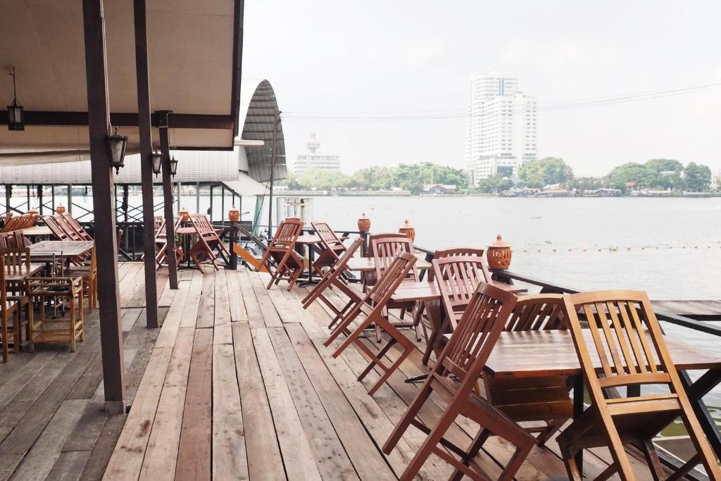una fila di tavoli e sedie su un molo con l'acqua di Kaloang home a Bangkok
