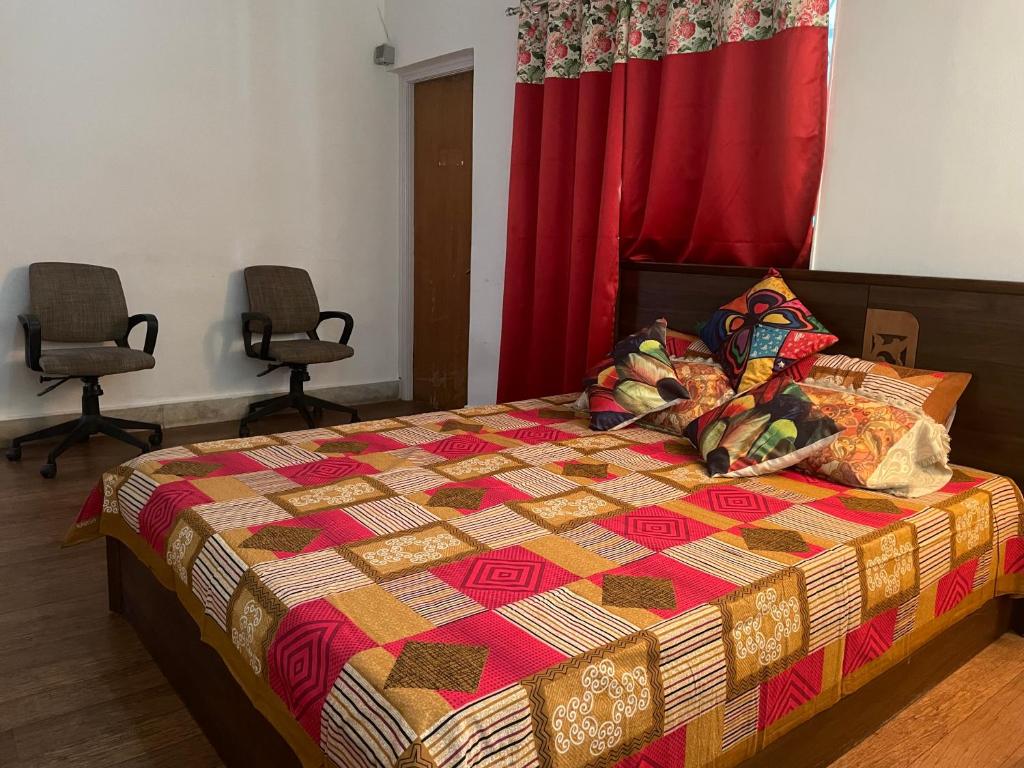 a bedroom with a bed with a colorful quilt and two chairs at Serene Living in Pune