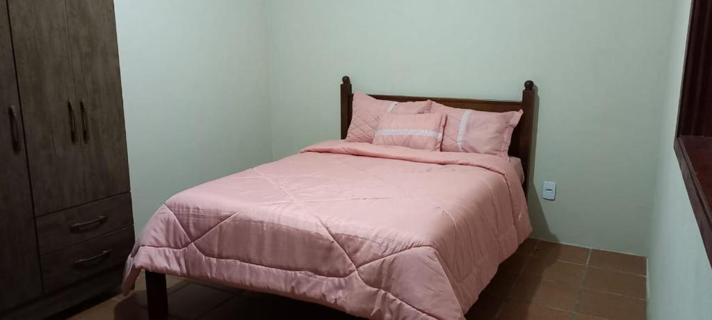 1 cama con edredón y almohadas rosas en Campo dos Sonhos en Serra Negra