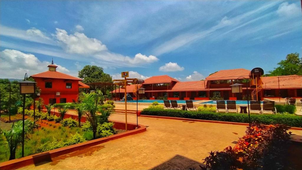 a resort with a pool and a red building at MAP RESORT in Alibaug