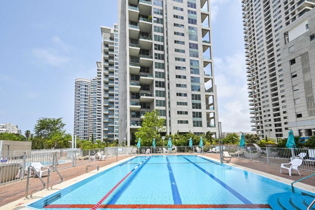 a swimming pool with a tall apartment building in the background at Mountain Vision by HolyGuest in Tel Aviv