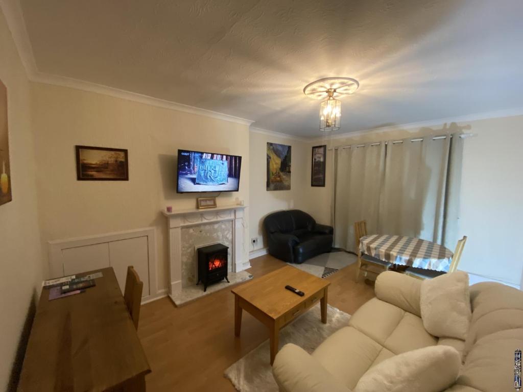 a living room with a white couch and a fireplace at Private Lounge and Double Room in Kilwinning