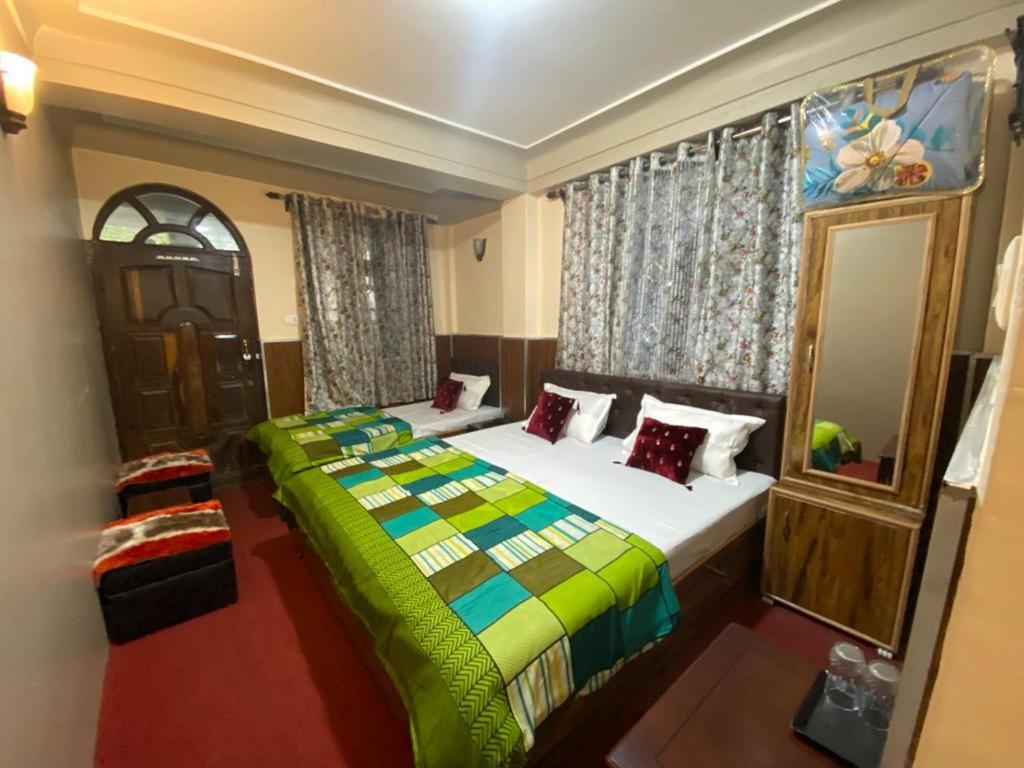 a bedroom with a bed with a green comforter at MAMTA HOMESTAY in Darjeeling