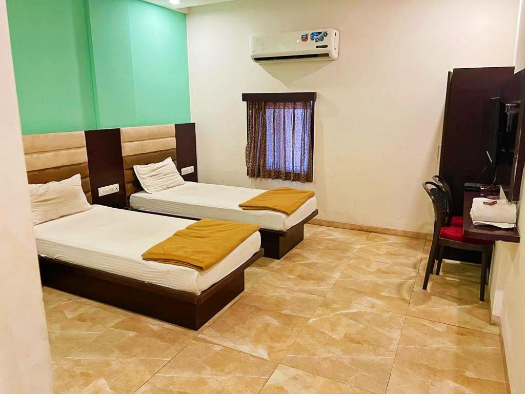 a room with two beds and a chair in it at Hotel Narmada in Lāchharas