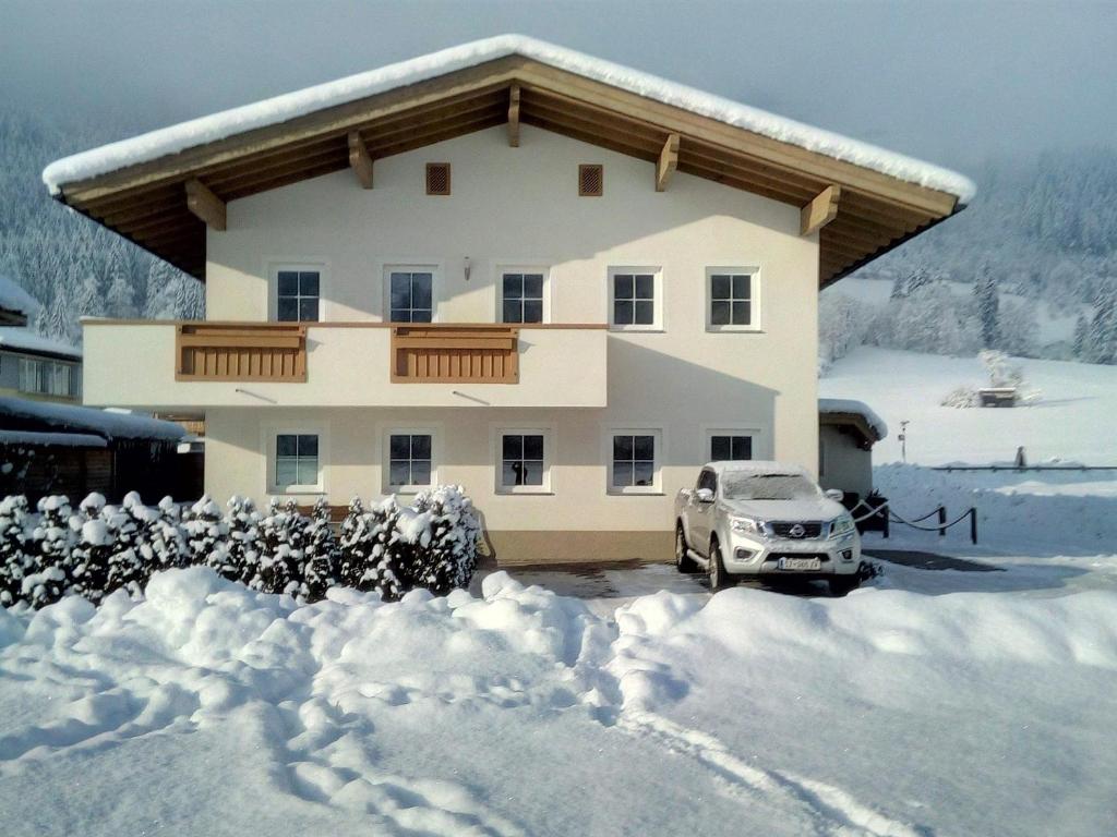 a house with a car parked in the snow at Landhaus Sporer in Aschau