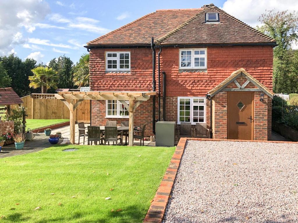 a brick house with a garden and a patio at Well Cottage in Itchingfield