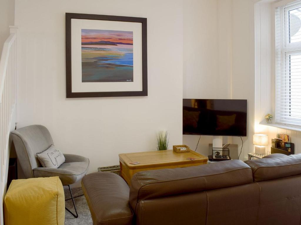 a living room with a couch and a tv at Hunter Links Cottage in Prestwick