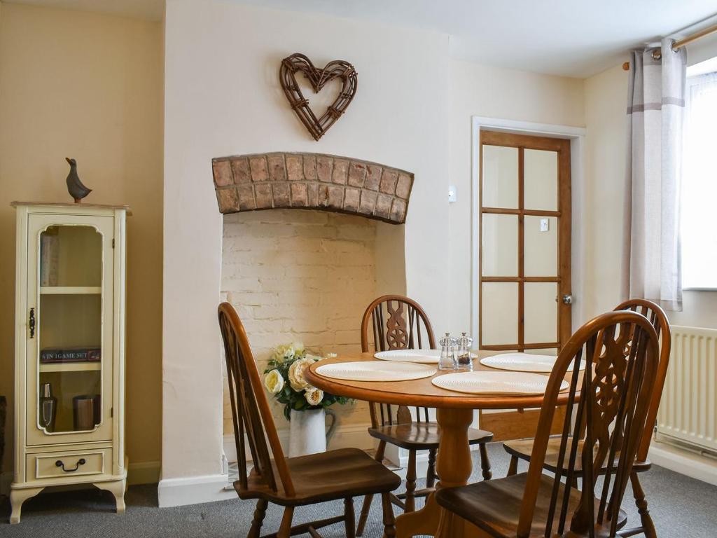 uma sala de jantar com uma mesa e uma lareira de tijolos em Peppercorn Cottage em Enderby