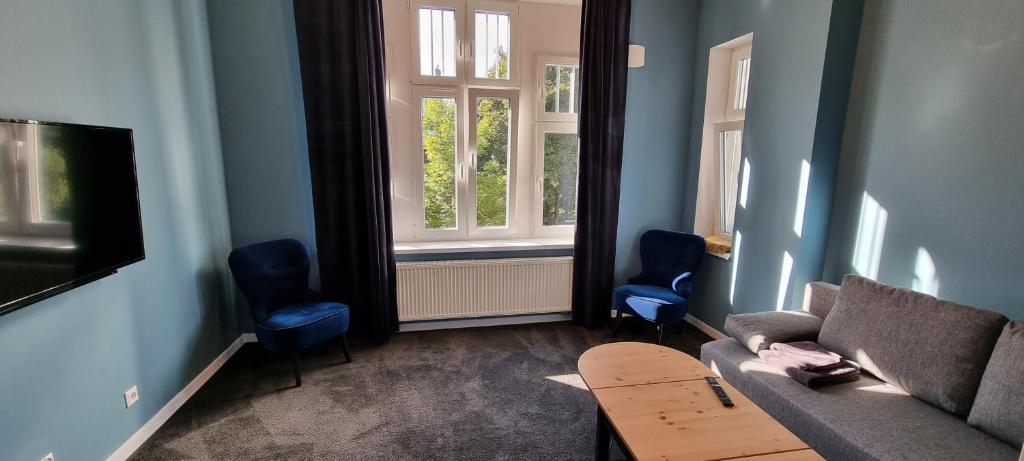 a living room with a couch and two blue chairs at Apartamenty Chorzów obok Parku Śląskiego in Chorzów