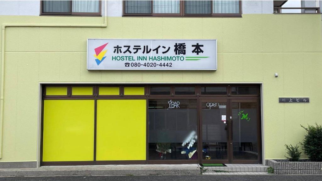 un magasin avec des portes jaunes et un panneau sur un bâtiment dans l'établissement Hostel Inn Hashimoto, à Hashimoto