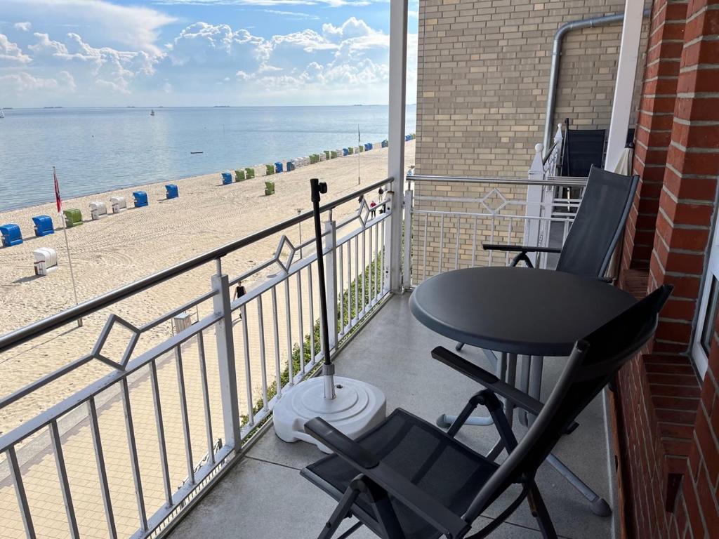 een balkon met een tafel en stoelen en het strand bij Nordland Appartements - Wohnung Südfall in Wyk auf Föhr