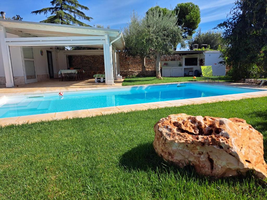 een grote rots in het gras naast een zwembad bij LA CASA DI BEL in Monopoli
