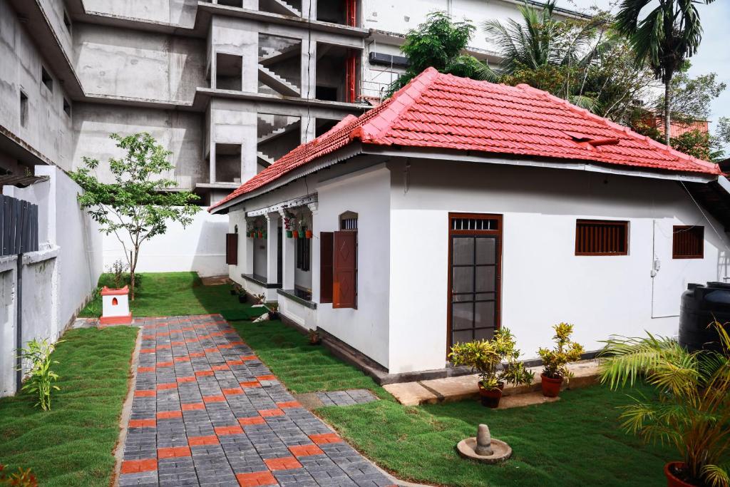 una pequeña casa blanca con techo rojo en Bobbys Corner en Alleppey