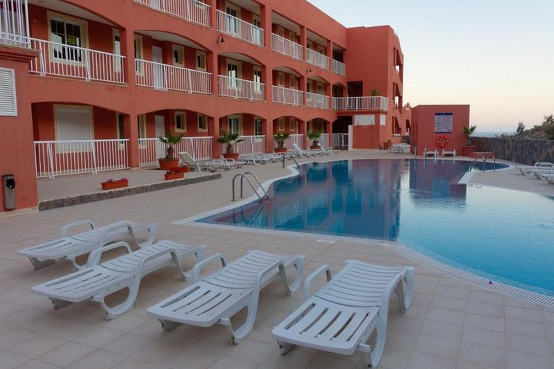 hotel z basenem z białymi stołami i krzesłami w obiekcie Apartamento Vista Esmeralda en Playa Paraiso w mieście Costa Calma